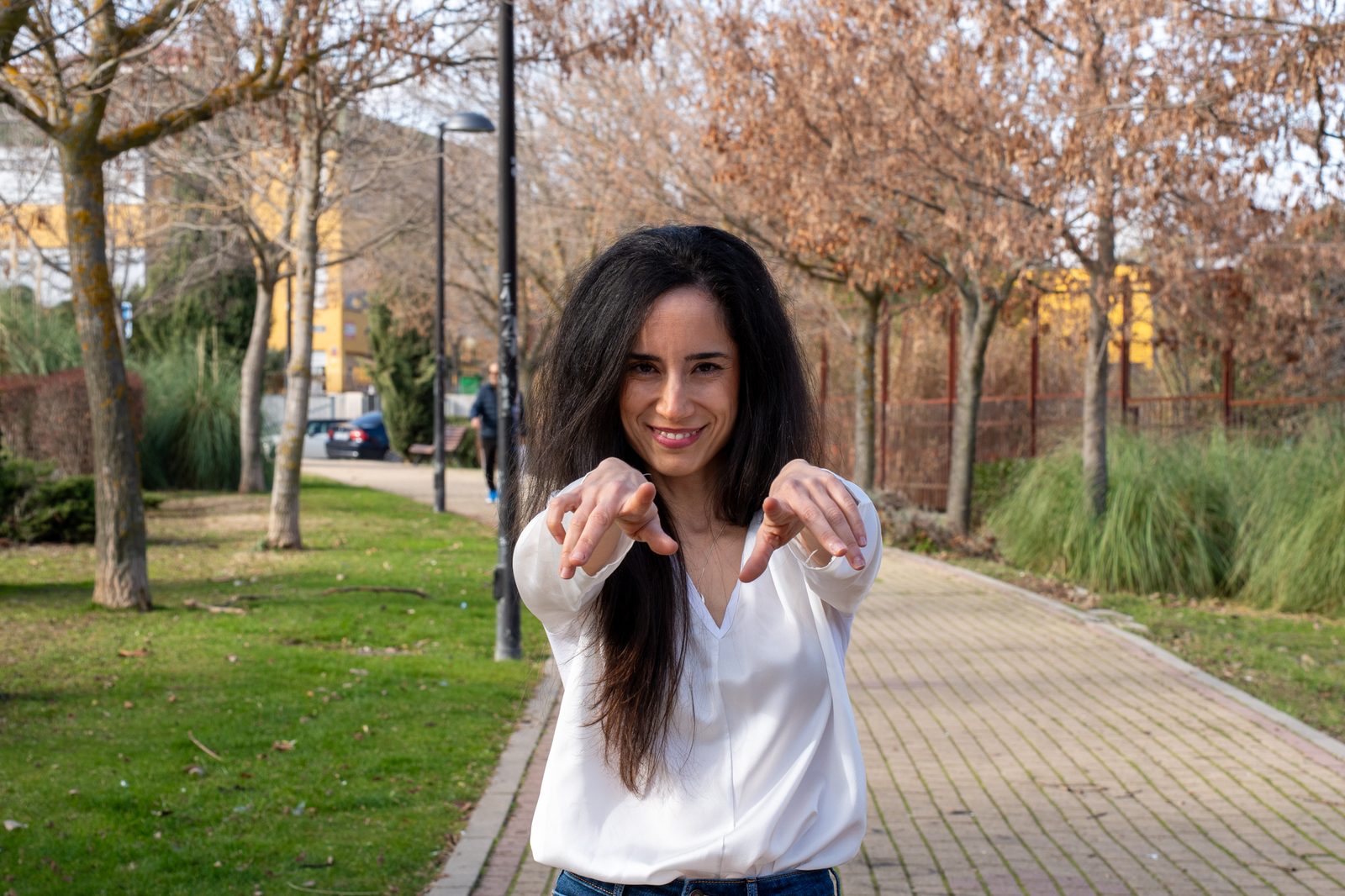 Diana Texeira señalando a cámara, sonriendo, en un parque