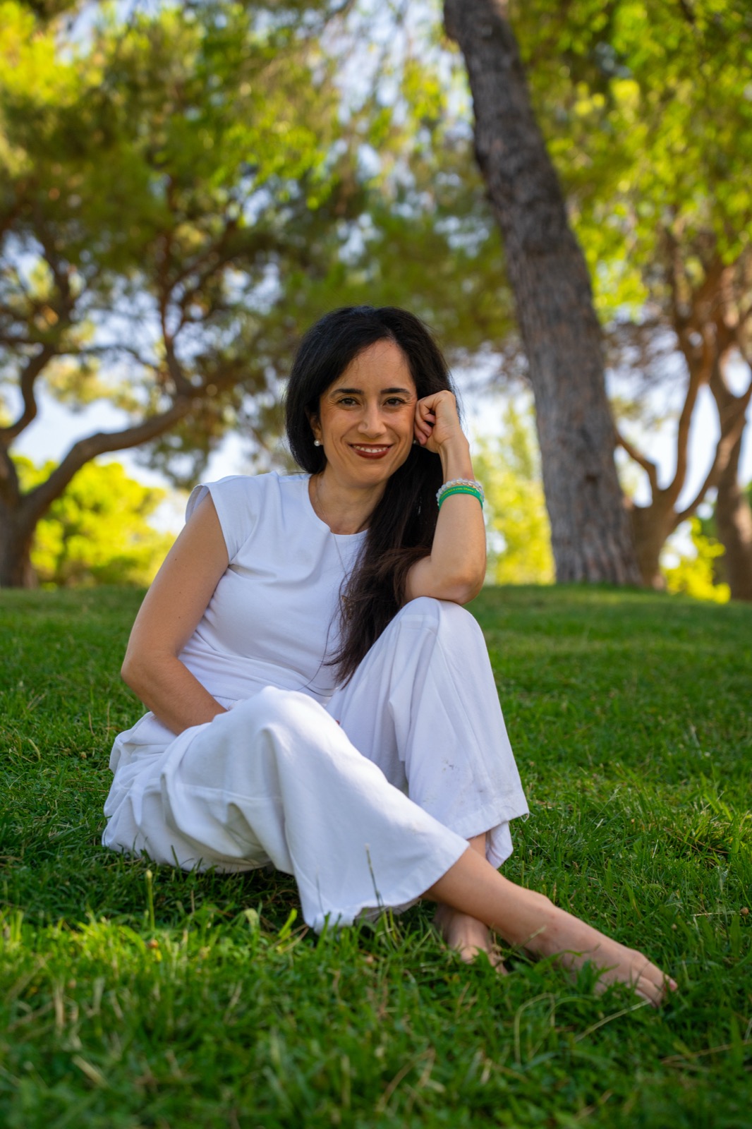 Diana Texeira sentada en la hierba, en un entorno natural, sonriendo con calma